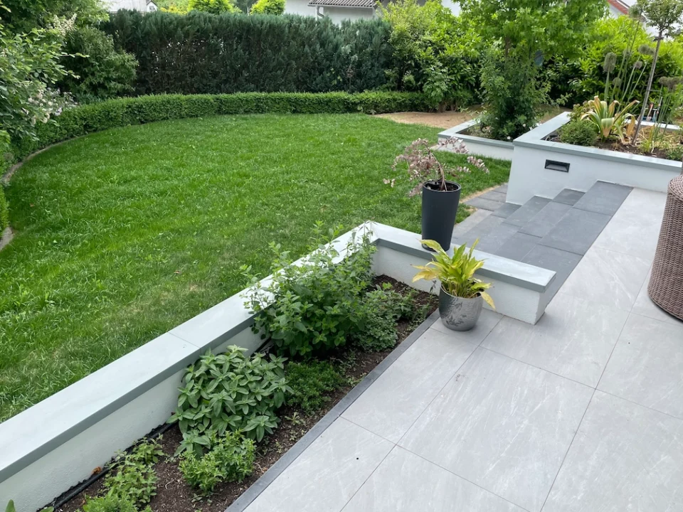 Moderne Terrasse mit Stufen zum grünen Garten, harmonische Anmutung